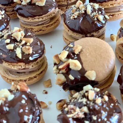 Macarons dipped in chocolate ganache and topped with chopped nuts